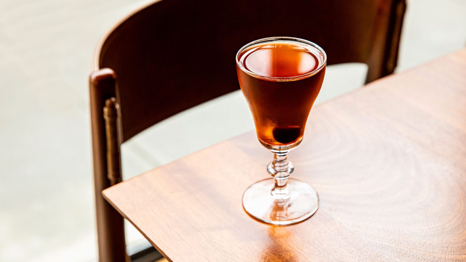 A brown-hued drink in a glass on a table